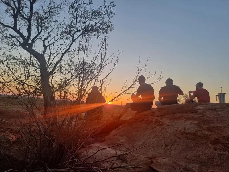 vier Männer auf einem Stein im Karijini Nationalpark im Sonnenuntergang