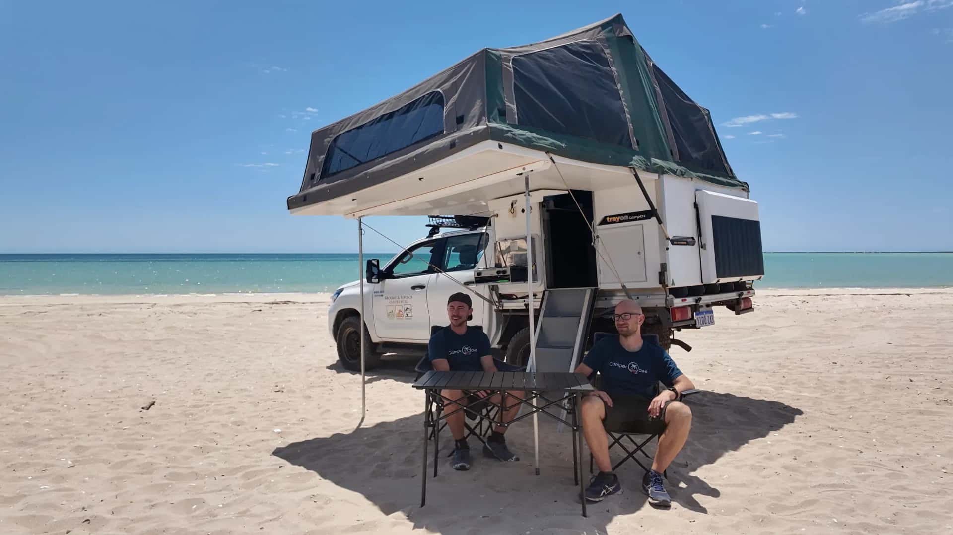 Allradcamper am Strand in Westaustralien mit aufgebauter Wohnkabine und zwei Herren, die in Stühlen davor sitzen