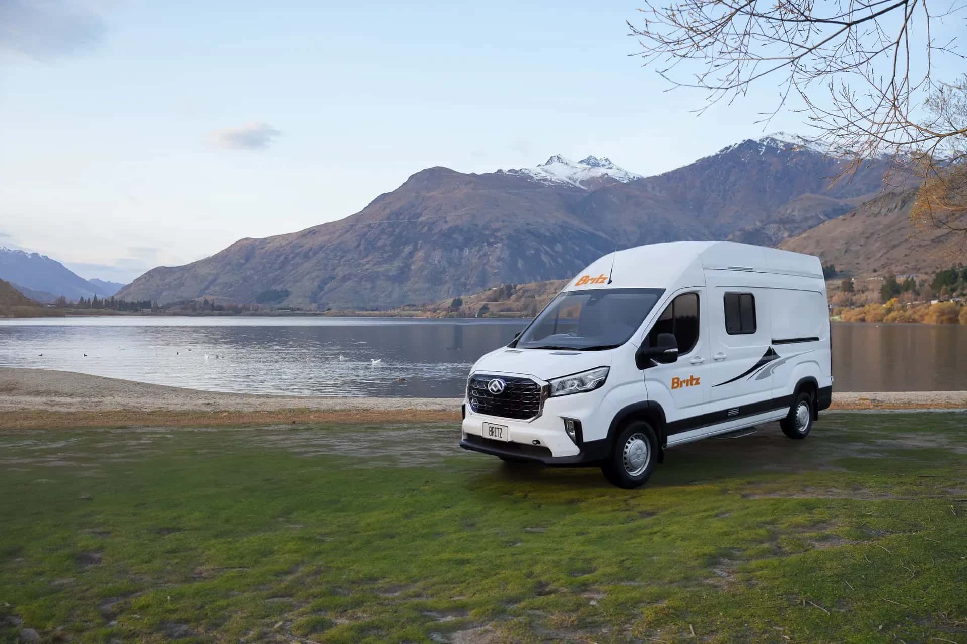 Hitop Camper von Britz Rentals für 2 Personen fahrend auf einer schmalen Straße zwischen Bäumen in Neuseeland