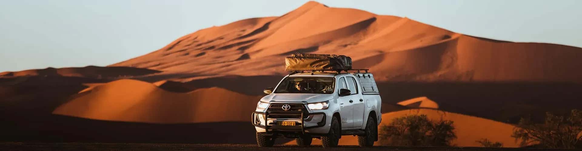 Hilux mit Dachzelt von Asco Car Hire vor Düne in Wüste in Namibia