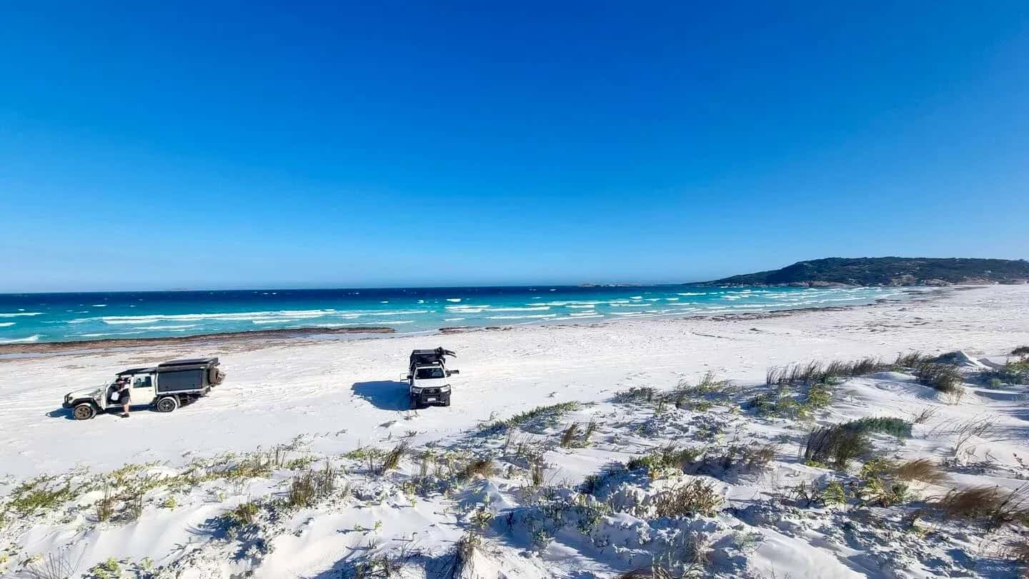 Drei Allradcamper fahren hintereinander am Strand in Esperance