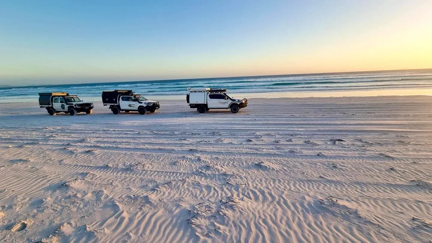 Drei Allradcamper fahren hintereinander am Strand in Esperance