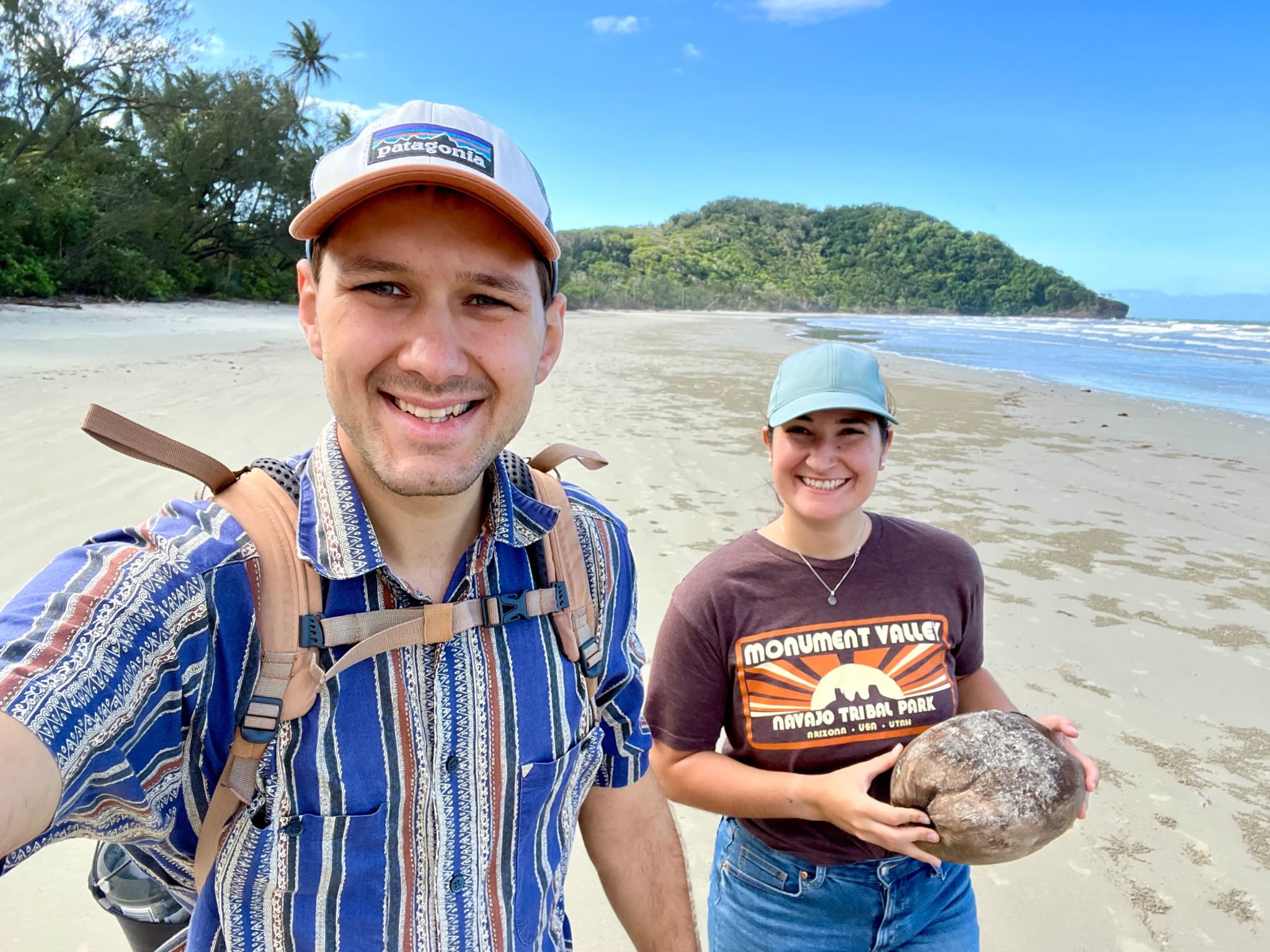 Junges Paar mit einer Kokosnuss in der Hand am Strand im Daintree Rainforest