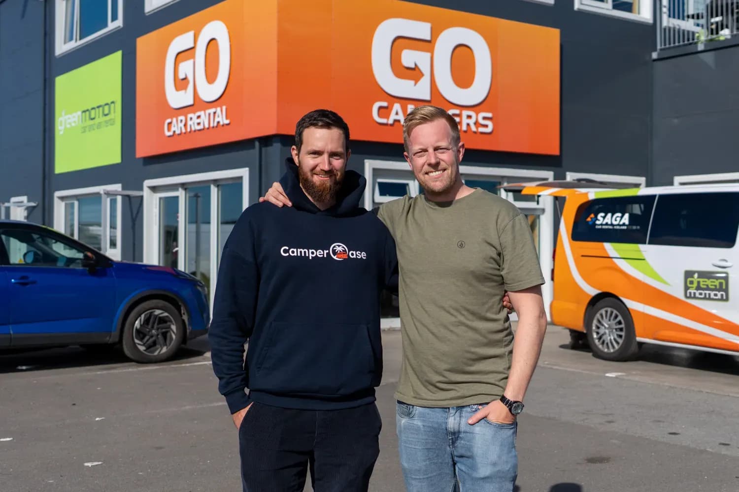 Vertreter von CamperOase und Go Campers vor der Mietstation mit orangefarbenem Go-Campers-Schild in Island.