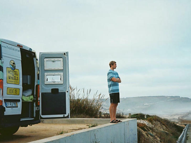 Mann steht vor Camper in Portugal und blickt aufs Meer