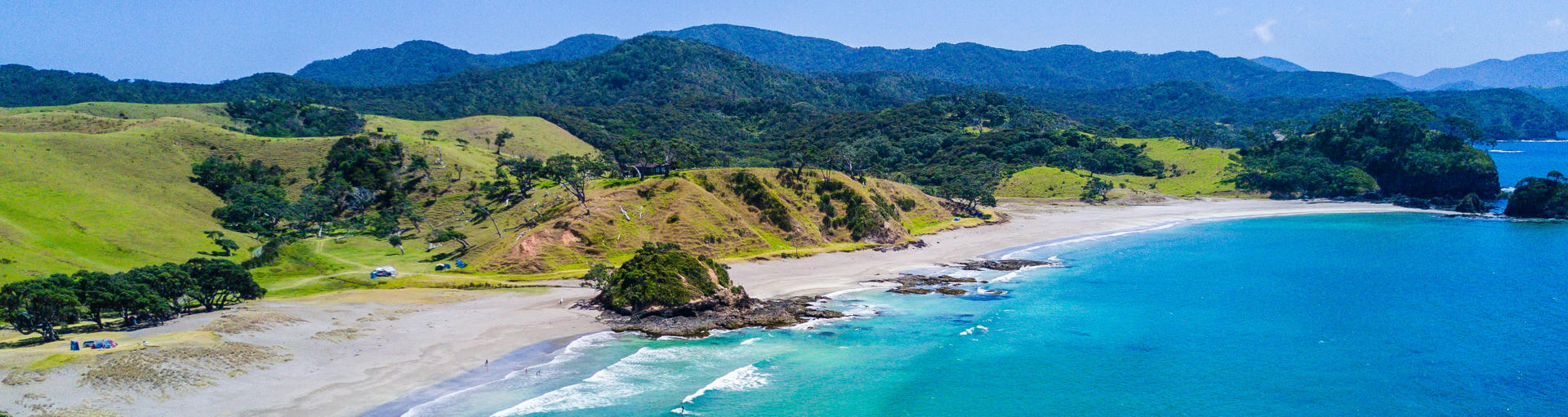natürlich Landschaft in den Bay of Islands Neuseeland mit grünen Wiesen einer Bucht mit Strand und klarem Wasser.