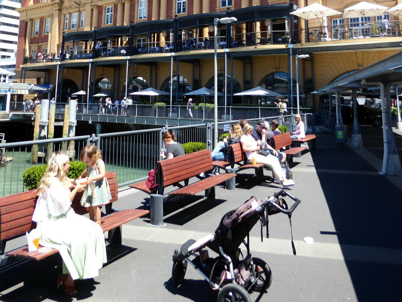 Menschen sitzen auf Bänken in der Sonne in Auckland