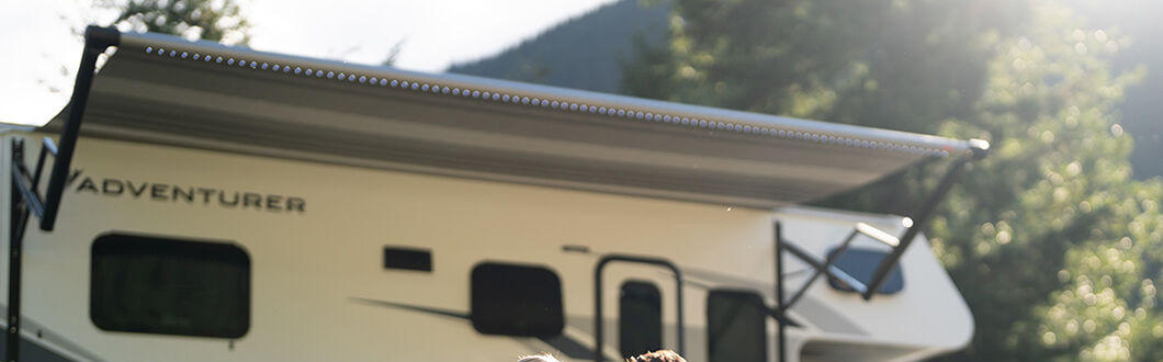 Der Class C Motorhome-Medium von Fraserway RV geparkt auf einer Wiese mit einem Paar davor sitzend in Kanada