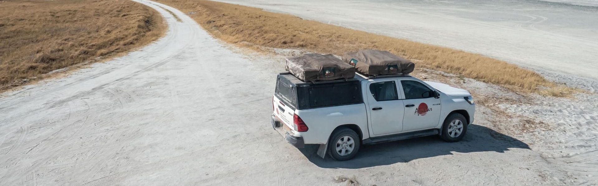 Der Budget Toyota Hilux 4 Pax von AfriCar Car Hire geparkt mitten in einer Sandlandschaft in Namibia