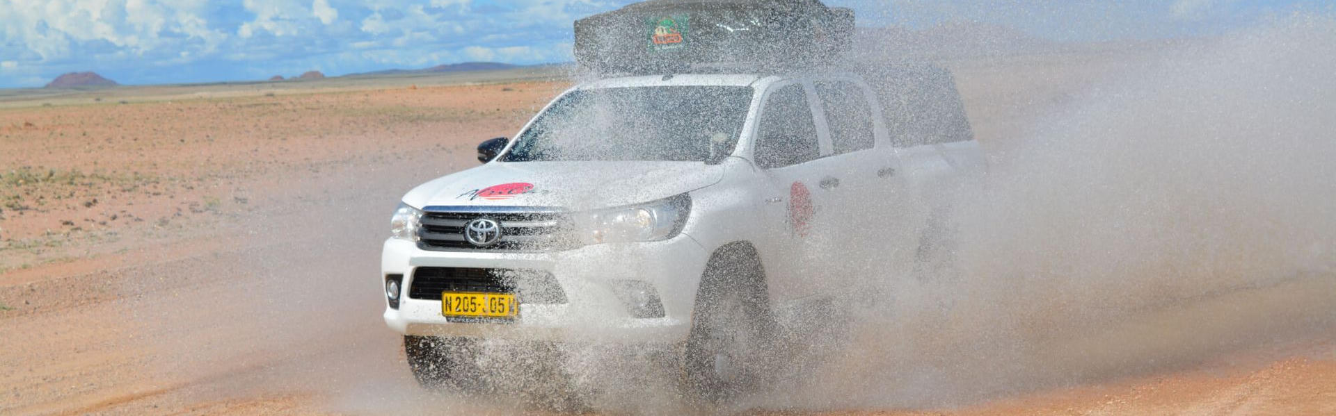 Der Premium Toyota Hilux 2 Pax von AfriCar Car Hire bei einer Offroad Durchfahrt auf Sand in Namibia