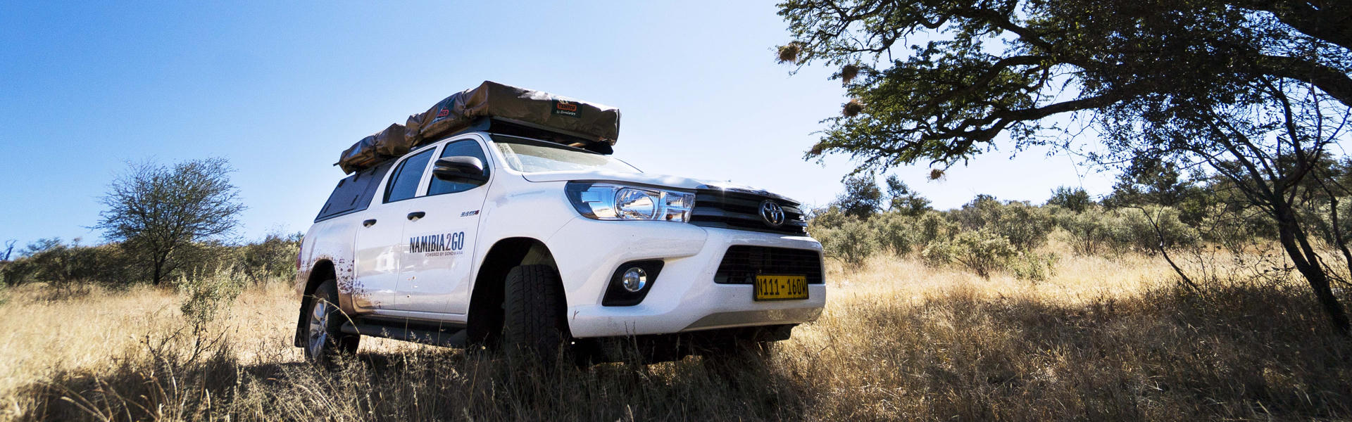 Toyota Hilux DC Camping Budget von Namibia2Go in trockener Graslandschaft in Namibia