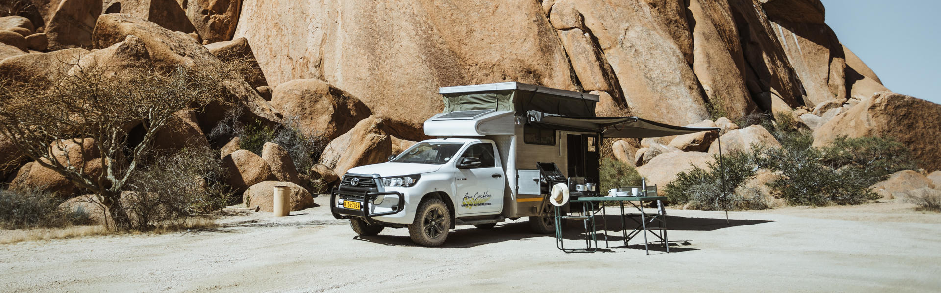 Budget VKK Hilux SC Bushcamper von Asco Car Hire in Namibia vor Felsformation