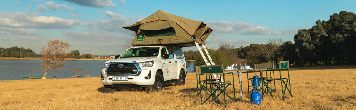 Der Toyota DOUBLE CAB 4 Pax von Britz Africa in Oase mit augebauten Zelten, Campingtisch und Stühlen.