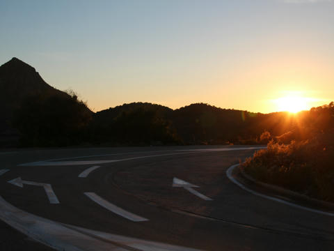 Straße mit Kurve und untergehender Sonne
